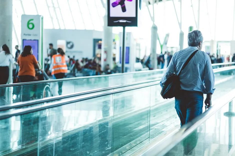 Traveler walking through an airport terminal concourse with a moving walkway